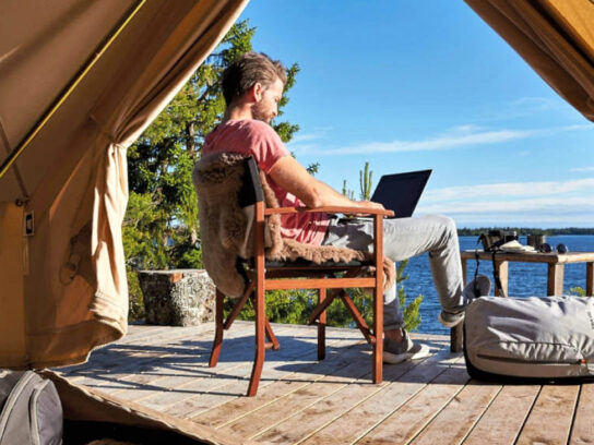 Photo of a man in a glam tent working on a lap top