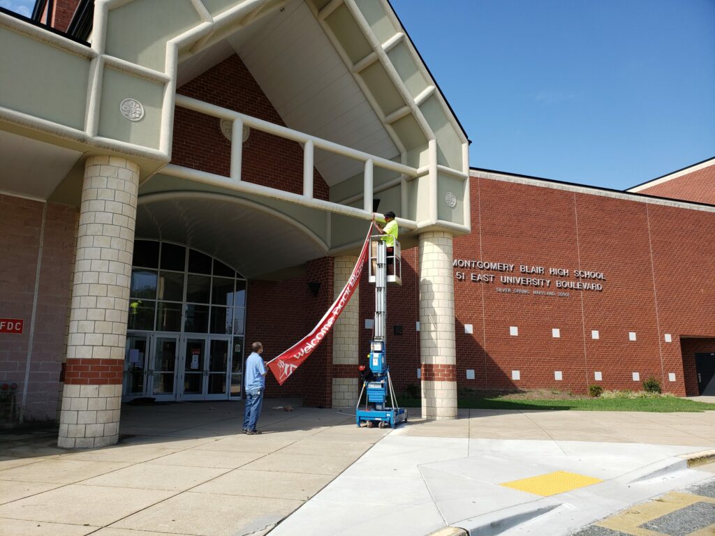 photo of bright welcome back blazers sign being hung on the front entrance