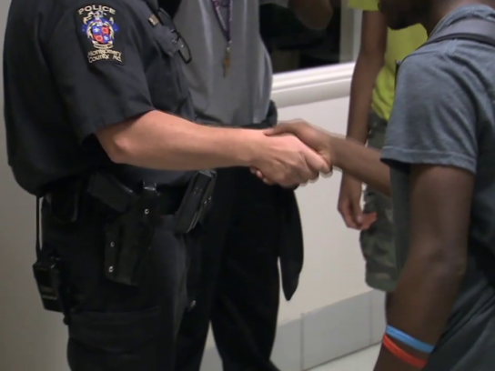 photo of school resource officer shaking hands with student