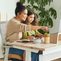 mother and daughter at table looking at laptop