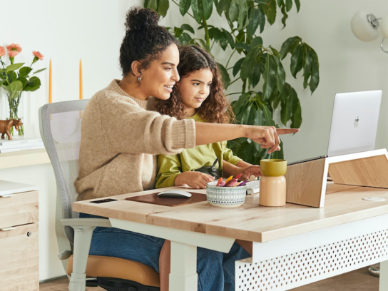 mother and daughter at table looking at laptop