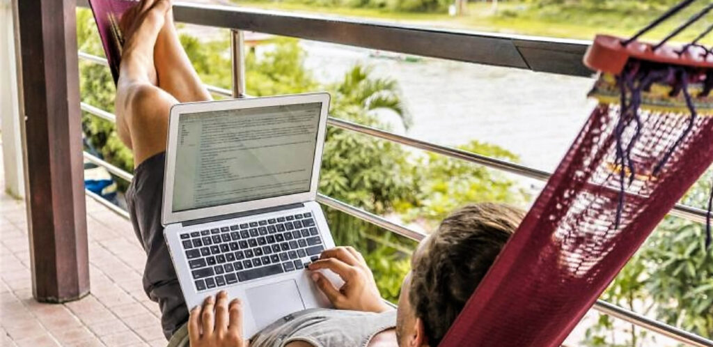 photo of man in a hammock working on a lap top