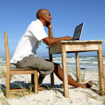 photo of Man working at his desk on the beach