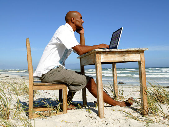 photo of Man working at his desk on the beach