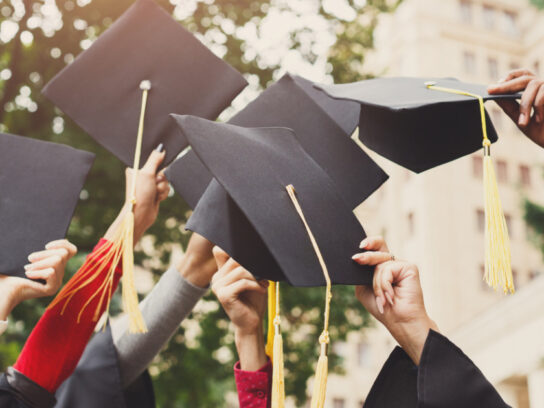 photo of group of graduates throwing graduation caps in the air