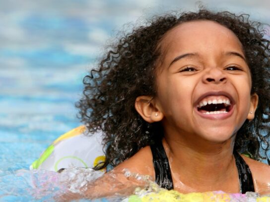 photo of jubilant kid swimming in a pool