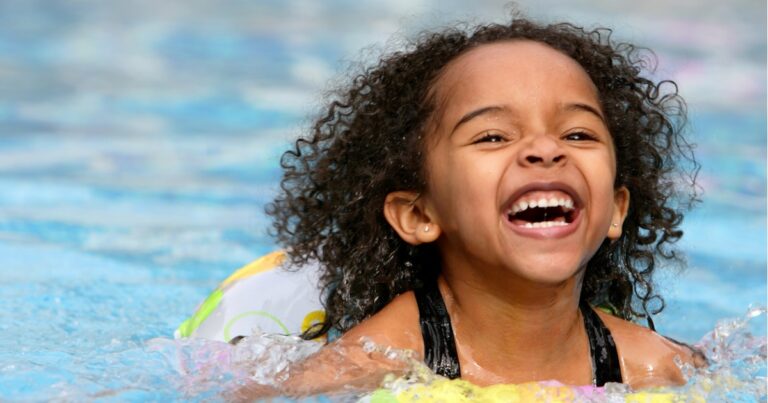 photo of jubilant kid swimming in a pool