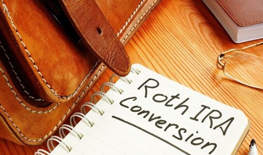 photo of notebook with message roth ira conversion on table next to a briefcase