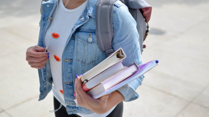Student with backpack on holding books in their hand.