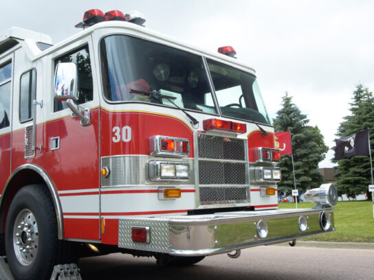 photo of A fire truck parked on the road with stoppers around a wheel