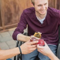 photo of three men toasting, one in a wheelchair