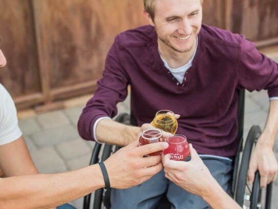 photo of three men toasting, one in a wheelchair