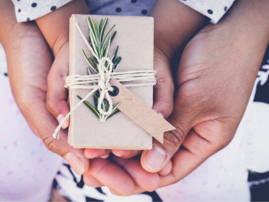 parents and child holding eco gift box with brown tag