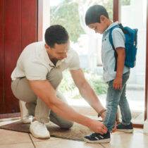 photo of father and son adjusting shoes at home getting ready for school