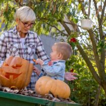 photo of grandmother with toddler working on carving a pumpkin